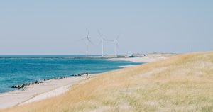 Wind turbines spinning by a vibrant seashore